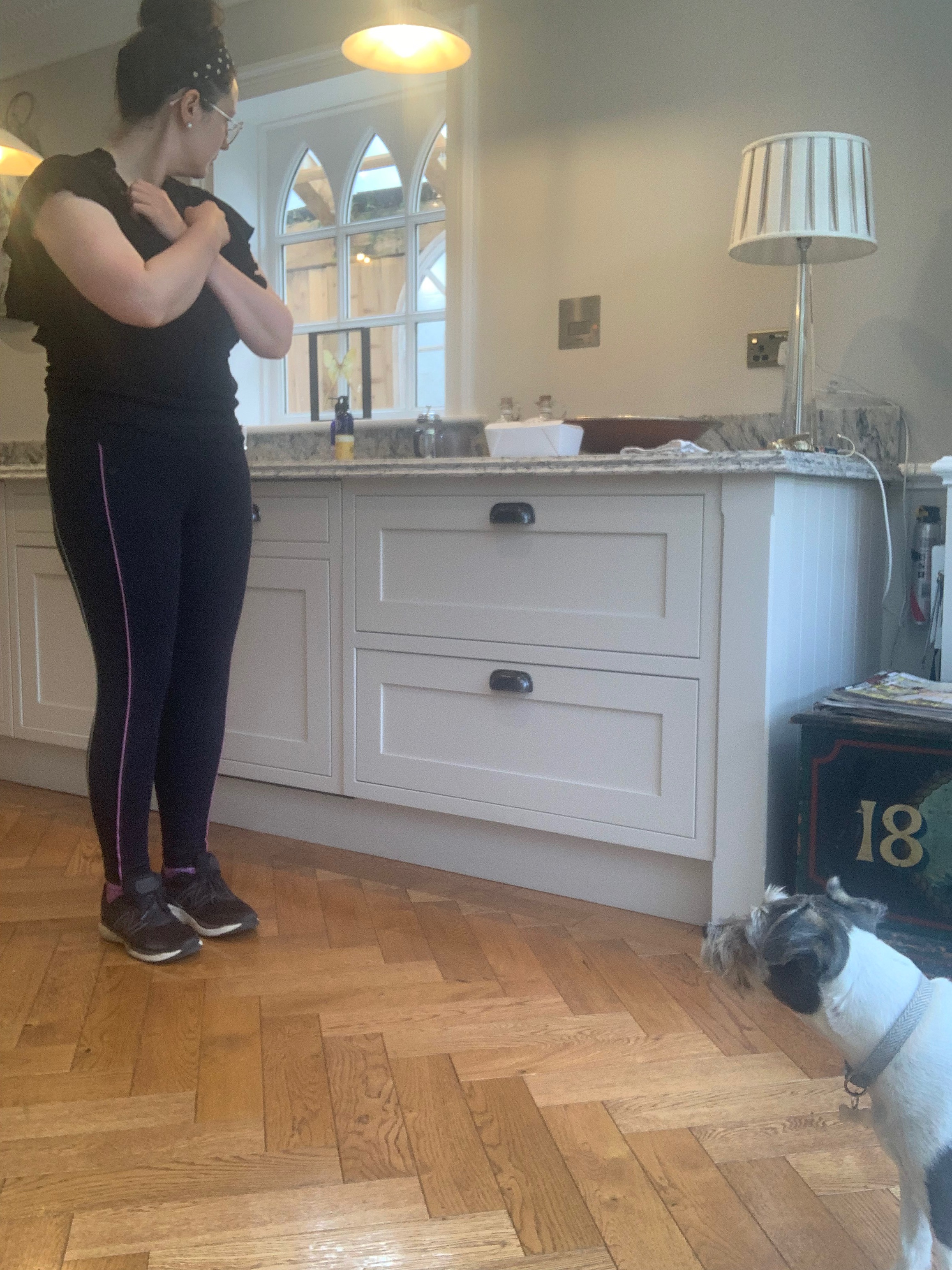 Lisa stands with her arms crossed while a dog looks at her 